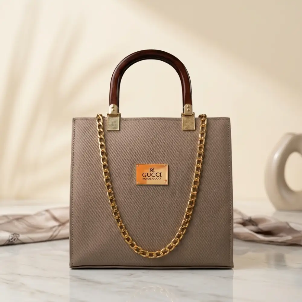 Light beige structured Saffiano leather satchel bag with dark wooden handle and gold chain strap.