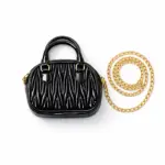 Women's black textured mini dome handbag featuring top handle and gold chain strap