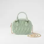 Women's mint green textured mini dome handbag featuring top handle and gold chain strap