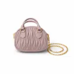 Women's dusty blush textured mini dome handbag featuring top handle and gold chain strap