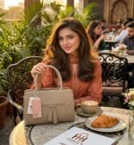 Warm khaki neutral handbag with top handles and front zipper tassels with model