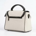 Rear view of FOXJAZZ off-white leather handbag showing back zip pocket and black edge piping on a studio background.