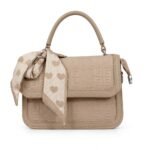 An elegant beige structured top-handle handbag featuring a repeating geometric embossed pattern and silver hardware, set against a plain white background. A tan and cream twilly scarf with heart patterns is tied decorative to the left side of the rigid handle.