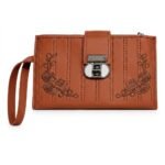 A rust-colored faux leather women's long wallet, designed as an embroidered wristlet clutch. The rich terracotta-brown surface features distinctive parallel vertical stitching lines and symmetric corner rose embroidery patterns in deep brown thread. Securing the wallet centrally is a prominent metallic twist-lock mechanism with a smooth white insert. A rust wristlet strap is attached.