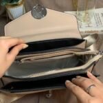 Hand expanding the inner pockets of the CIEICI color block bag showing spacious storage capacity.
