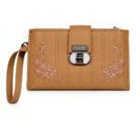 A light caramel-brown faux leather women's long wallet designed as an embroidered wristlet clutch, featuring a fine pebble-grain texture. Symmetrical floral rose embroidery in tan thread adorns the bottom corners, divided by parallel vertical stitching. A distinct central gunmetal turn-lock closure with a white insert and a tan wristlet strap complete the design.
