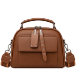 Warm cognac saddle brown top handle dome satchel purse with front pocket and studded zipper extensions.